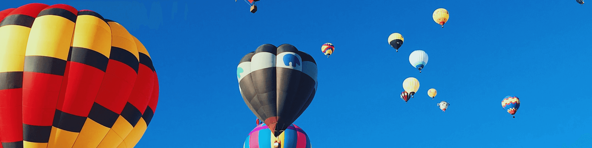 Bright sunny blue sky filled with colourful hot air balloons - cultivating curiosity and aimlessness
